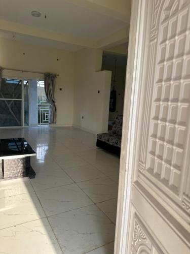 a living room with a large white tile floor at Kams Lodge Broadview, Idu in Furah