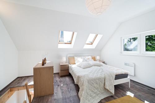 a white bedroom with a bed and two windows at M.F. in Chvalatice