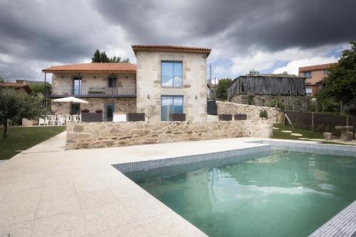a house with a swimming pool in front of a house at A Casa da Fonte Azul in Ourense