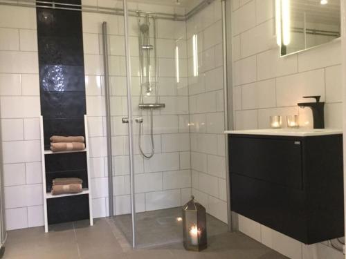 a bathroom with a shower and a sink with a candle at Egen lägenhet i charmig miljö i Linköping V in Vikingstad