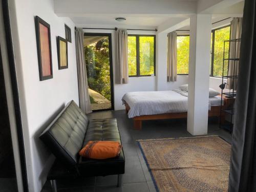Rustic Charm Cliffside Retreat في Jaibalito: غرفة نوم بسرير واريكة ونوافذ