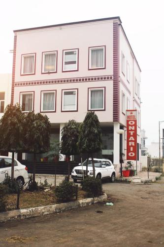 a pink building with cars parked in front of it at Hotel Ontario in Patiāla