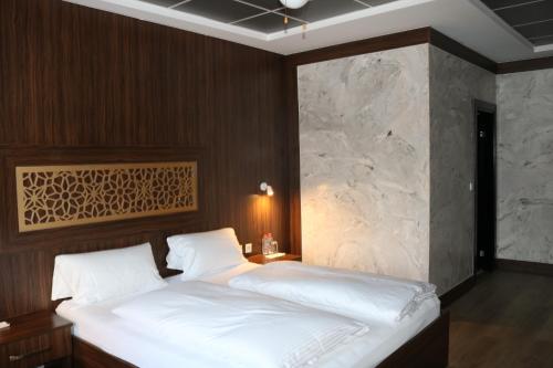 a bedroom with a large white bed with a stone wall at Louis Hotels in Schmitten