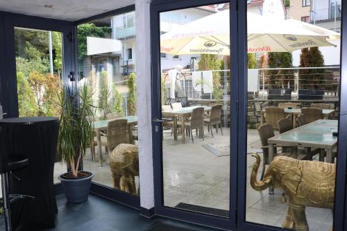 a restaurant with glass doors and a patio with tables at Louis Hotels in Schmitten