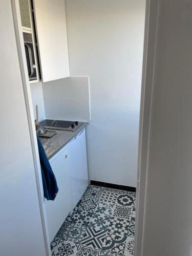 una pequeña cocina blanca con suelo de baldosa blanco y negro en Studio pour 2 personnes avec Balcon Metro Marcel Sambat, en Boulogne-Billancourt