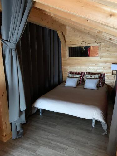 un lit dans une chambre avec un plafond en bois dans l'établissement L'Orpin Givré - Chalet Limoselle avec grande mezzanine, à Ventron