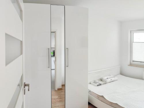 Schlafzimmer mit weißen Wänden, einem Bett und einem Spiegel in der Unterkunft Apartment Szwed-Sniadowskiej Residence in Krakau