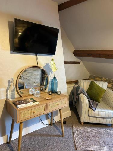 a living room with a table with a tv on the wall at Siam cottage guesthouse over 300 years old with Thai restaurant in Moreton in Marsh