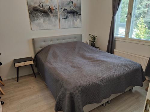 Un dormitorio con una cama con una manta gris. en Parvekkeellinen ja saunallinen kaksio Hyvinkäällä, en Hyvinkää