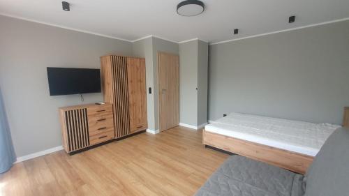 Schlafzimmer mit einem Bett und einem Flachbild-TV in der Unterkunft Słoneczny apartament in Augustów