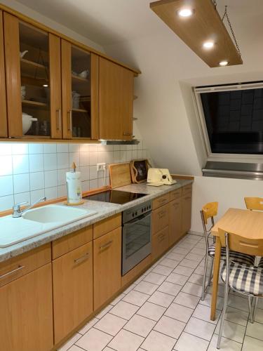 a kitchen with wooden cabinets and a sink and a table at Ferienwohnung Kranichnest in Neubrandenburg