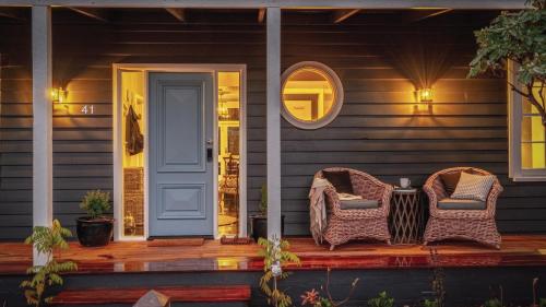 two wicker chairs sitting on the front porch of a house at Soma Trentham in Trentham
