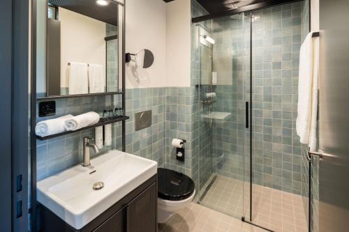 a bathroom with a sink and a glass shower at Tailormade Hotel LEO St Gallen in St. Gallen