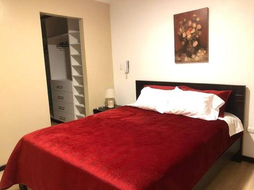 um quarto com uma cama com um cobertor vermelho em Condominio La Victoria, departamento em Cuenca