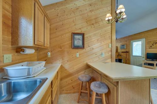 a kitchen with a sink and a counter with stools at Woodland Cabin with Fishing, ATV and Snowmobile Trails in Lake Nebagamon