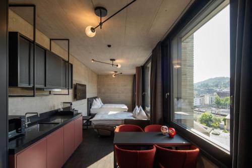 a room with a bed and a kitchen with a sink at Tailormade Hotel LEO St Gallen in St. Gallen
