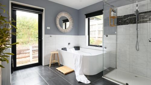 a bathroom with a white tub and a shower at Sutton Lodge Daylesford in Daylesford