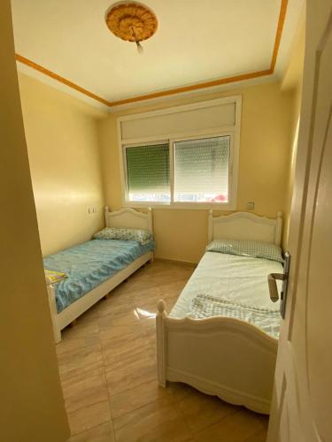 um quarto com duas camas e uma janela em APARTAMENTO moulay boslham em Kenitra