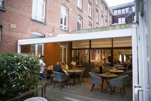 un groupe de personnes assises à des tables sur un patio dans l'établissement Alfa Inn, à Blankenberge