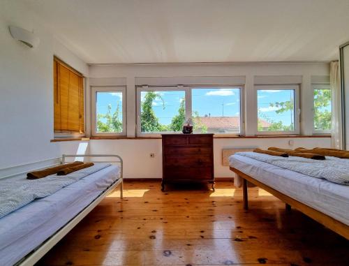 een kamer met 2 bedden, een bureau en ramen bij F13 Apartment in Pula