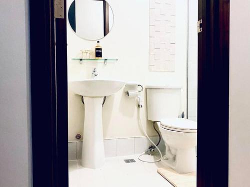 a bathroom with a sink and a toilet with a mirror at Aussie Shack - 2BR Modern Condo with Skyline View in Manila