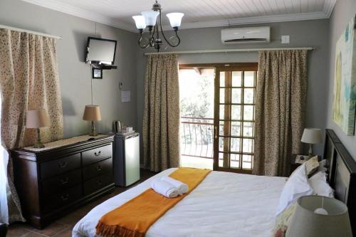 a bedroom with a bed with a dresser and a window at Khutse Guest House in Lephalale