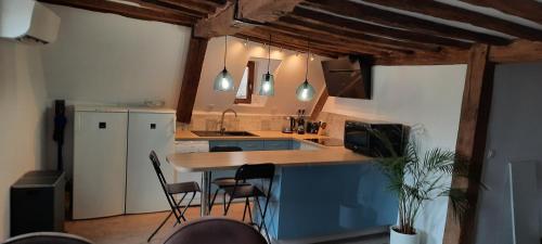 Il comprend une cuisine équipée d'un comptoir avec des chaises et d'un réfrigérateur. dans l'établissement appartement atypique, à Dijon