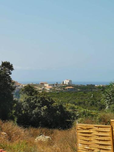 une clôture en bois au sommet d'une colline plantée d'arbres dans l'établissement Grande Chambre tout confort, à Bonifacio