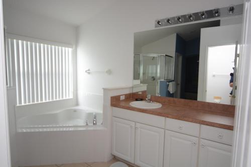 Baño blanco con lavabo y espejo en Elite Homes - Cumbrian Lakes en Kissimmee