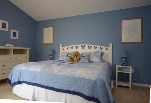 Un dormitorio azul con una cama con un osito de peluche. en Elite Homes - Cumbrian Lakes, en Kissimmee