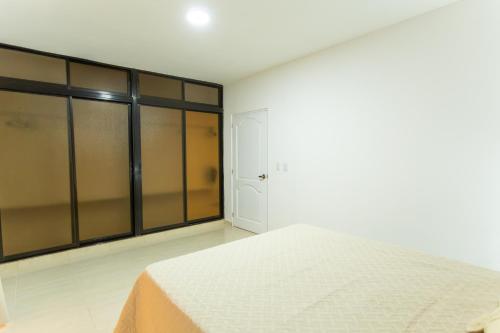 a white bedroom with a bed and glass walls at MB Apartment - A in San Felipe de Puerto Plata