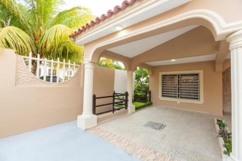 an entry to a house with an archway and palm trees at MB Apartment - A in San Felipe de Puerto Plata