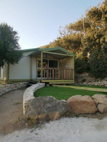 une maison avec une terrasse couverte et une cour ornée de rochers dans l'établissement Grande Chambre tout confort 3, à Bonifacio