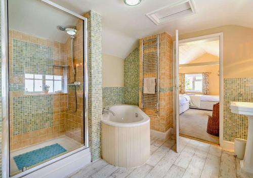 a bathroom with a tub and a shower and a sink at Coach House Cottage in Wickham Market