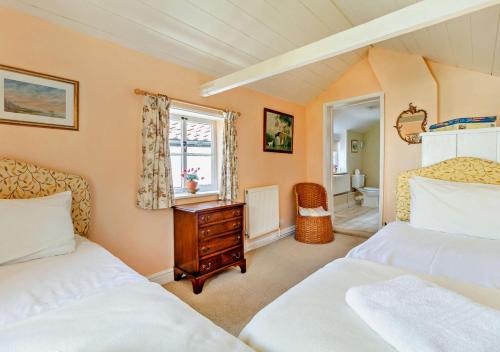 a bedroom with two beds and a desk and a window at Coach House Cottage in Wickham Market