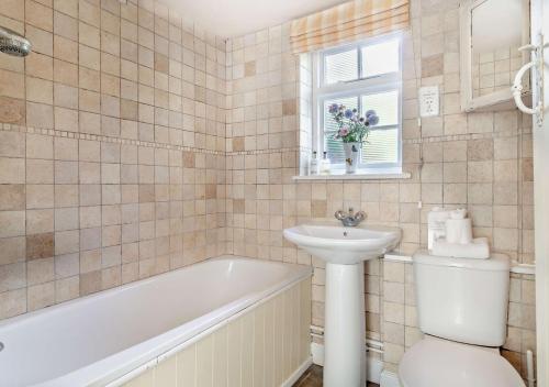 a bathroom with a tub and a sink and a toilet at Coach House Cottage Annexe in Wickham Market