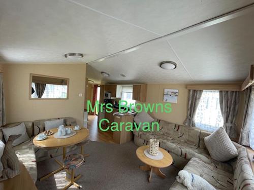 6 Berth, pet friendly caravan with decking في Little Clacton: غرفة معيشة مع أريكة وطاولة