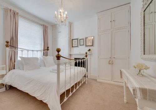 een witte slaapkamer met een bed en een kroonluchter bij La Ronessa in Aldeburgh