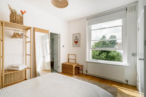 1 dormitorio con cama y ventana en Design-led flat in Camden on quiet street, en Londres