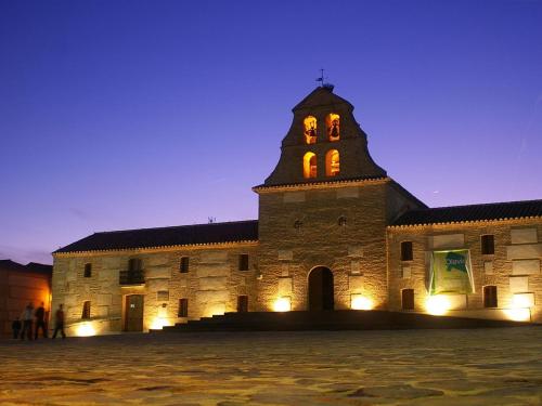 a large stone building with a clock tower at night at Vivienda Rural Ronda in Aldeaquemada