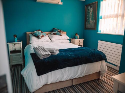 a bedroom with a bed with a blue wall at Seafarer's View - 6 bedroom townhouse in Cowes, parking & seaviews. in Cowes