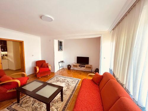 salon z czerwoną kanapą i telewizorem w obiekcie Gërmia House - Prishtinë w mieście Sofalija