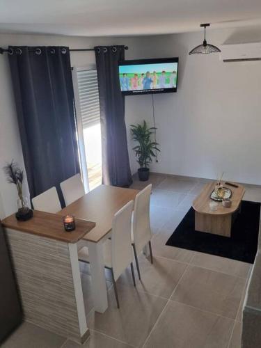 a dining room with a table and chairs and a tv at maison cosy avec cours in Avignon