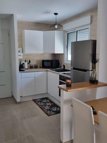 a kitchen with white cabinets and a stainless steel refrigerator at maison cosy avec cours in Avignon