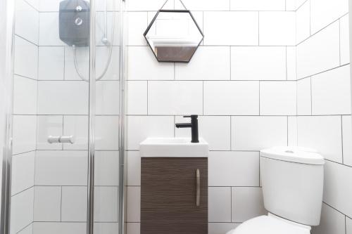 uma casa de banho em azulejos brancos com um WC e um lavatório em No5a, Studio Apartment, Willowbrook House em Bedworth