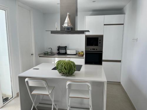una cocina con una isla blanca con una planta en Casa el Timple, en Costa Teguise