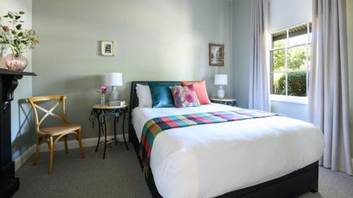 a bedroom with a bed with colorful pillows and a window at Casa Merenda Daylesford in Daylesford