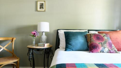 a bedroom with a bed with pillows and a table with a chair at Casa Merenda Daylesford in Daylesford