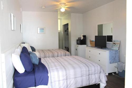 a bedroom with two beds and a television in it at Coastal Waters Studio 111 - Pool Side Studio in New Smyrna Beach