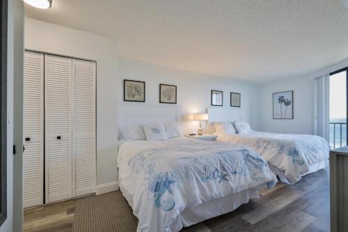 a white bedroom with two beds and a window at 1 Bedroom -1 Bath Ocean View Condo At Ocean Trillium 802 in New Smyrna Beach
